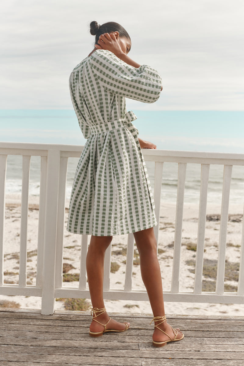 Wiggy Kit | Mini Square Neck Dress | Model wearing green and cream gingham print with beach in background