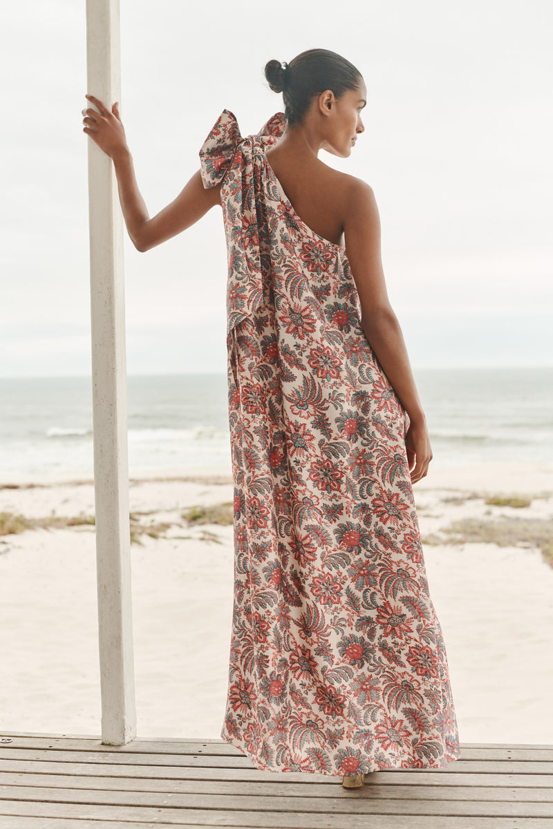 Wiggy Kit | Bay Dress (Pink Jungle Print) | Model wearing one-shoulder maxi dress in jungle print, with beach in background