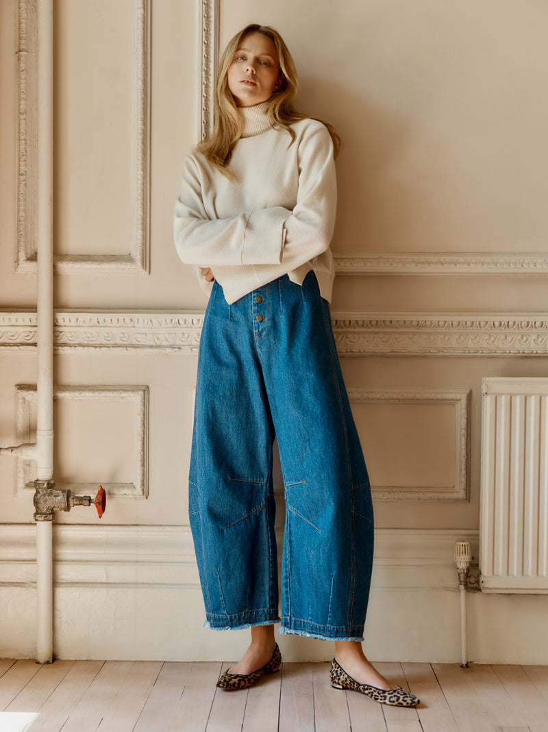 A model wearing the Wiggy Kit Inside Out Turtleneck in Ivory and Rancher Jean with arms folded.