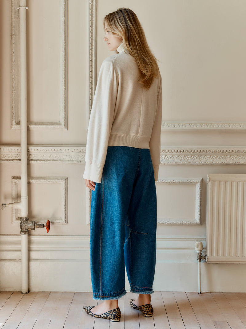 A model wearing the Wiggy Kit Inside Out Turtleneck in Ivory and Rancher Jean standing facing away.