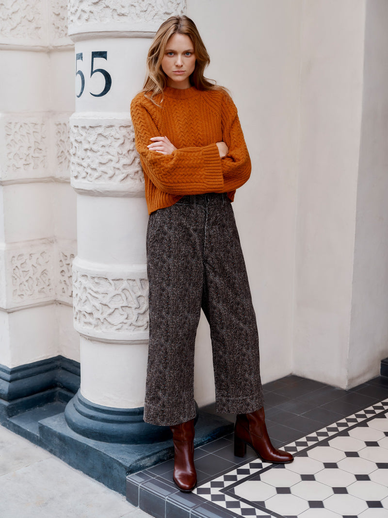 Wiggy Kit model wearing The Slouch Fisherman's Crew jumper and Cord Shore Pant leaning on a pillar.