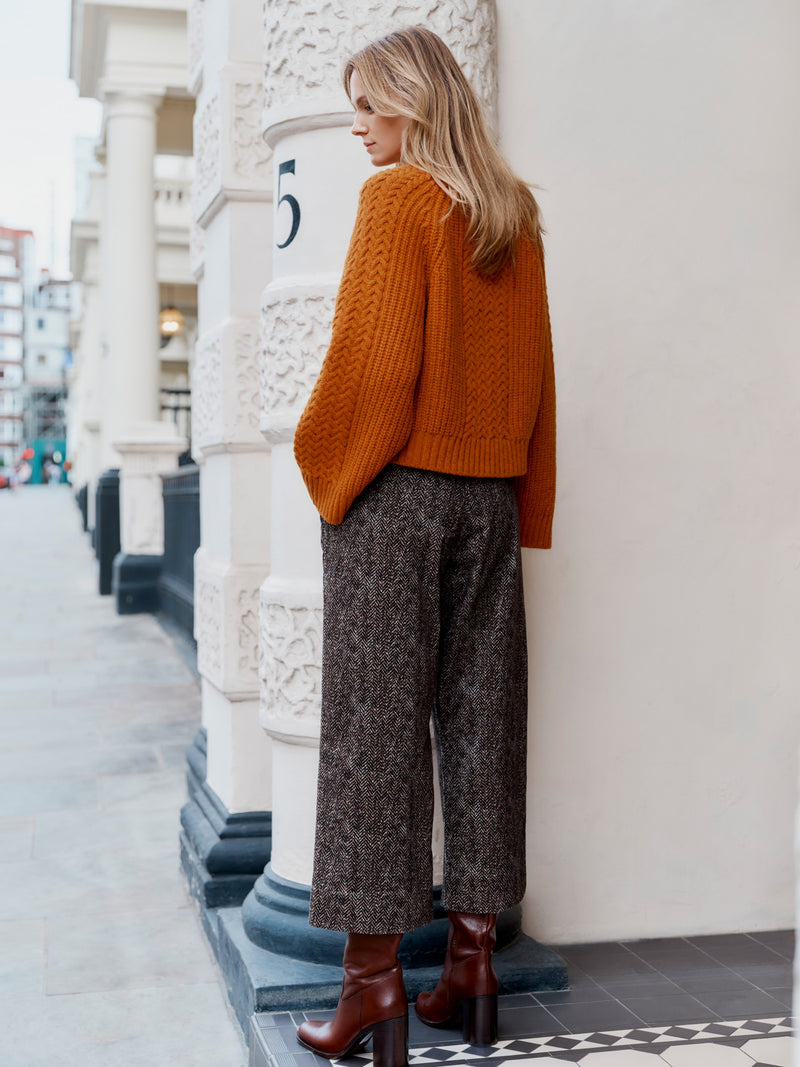 A model wearing the Wiggy Kit Cord Chore Pants and Orange Slouch Fisherman's Crew jumper stood facing away with hand in pocket.