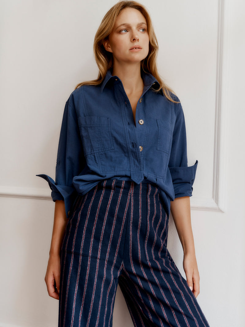 Wiggy Kit model wearing The Yonder Shirt and Ledbury Pant leaning on a wall in a grand house.