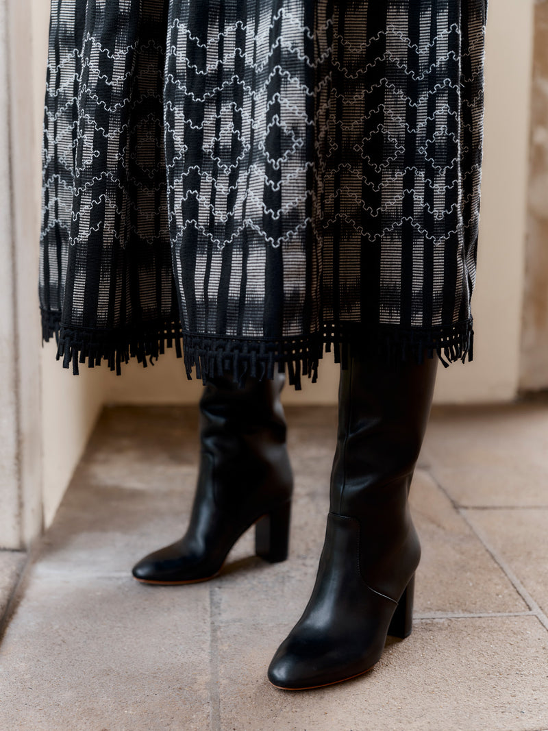 A model showing the hem of the Wiggy Kit Embroidered Goucho Skirt with black leather boots.