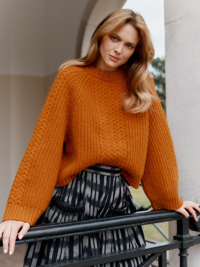 Wiggy Kit model wearing The Slouch Fisherman's Crew jumper and Embroidered Gaucho Skirt leaning on balcony railing.