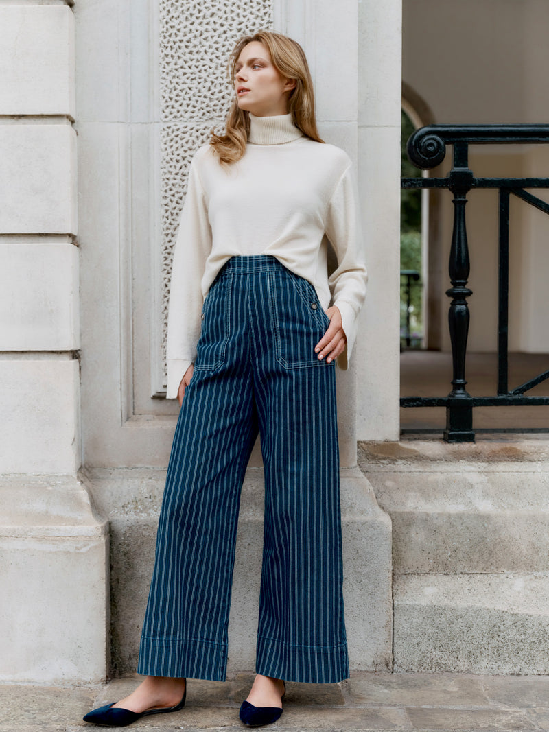 A Wiggy Kit model wearing the The Striped Jean outside a grand entrance.