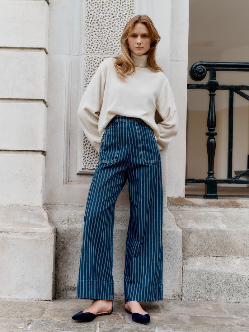 A Wiggy Kit model wearing the The Striped Jean outside a grand entrance.