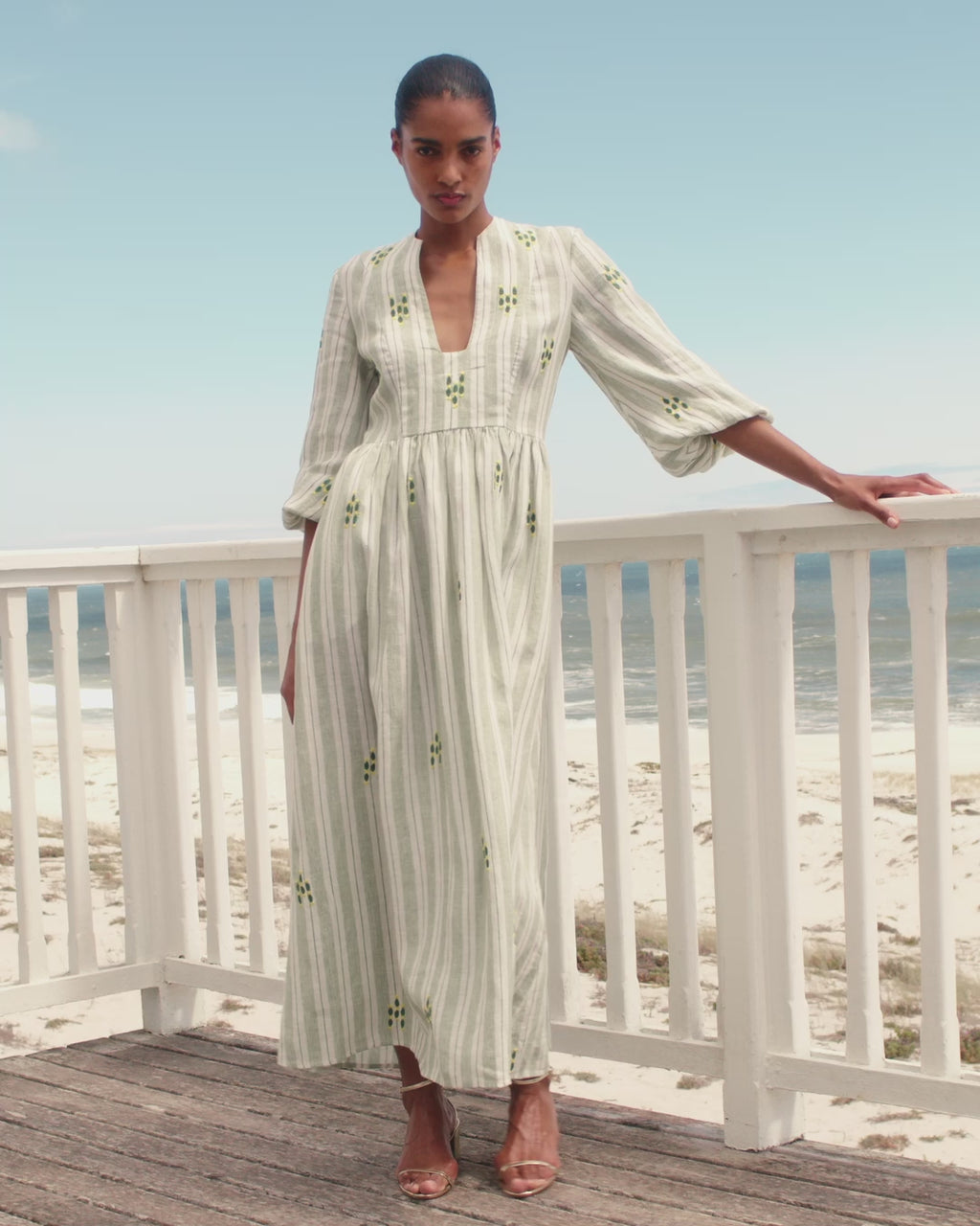 Wiggy Kit | Loulou Dress (Green Stripe) | Model wearing striped beige maxi dress with beach in background.