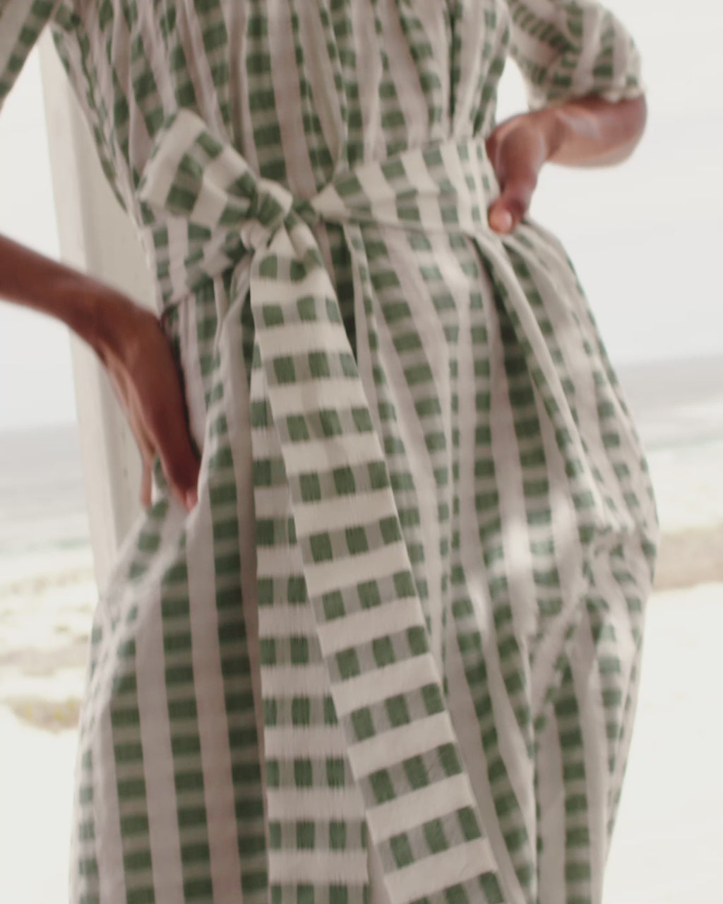 Wiggy Kit | Bastide Dress | Model wearing green and white gingham dress with beach in background