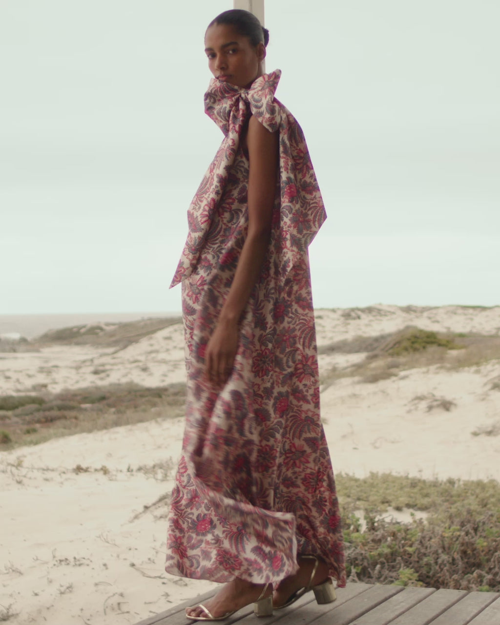 Wiggy Kit | Bay Dress (Pink Jungle Print) | Model wearing one-shoulder maxi dress in jungle print, with beach in background